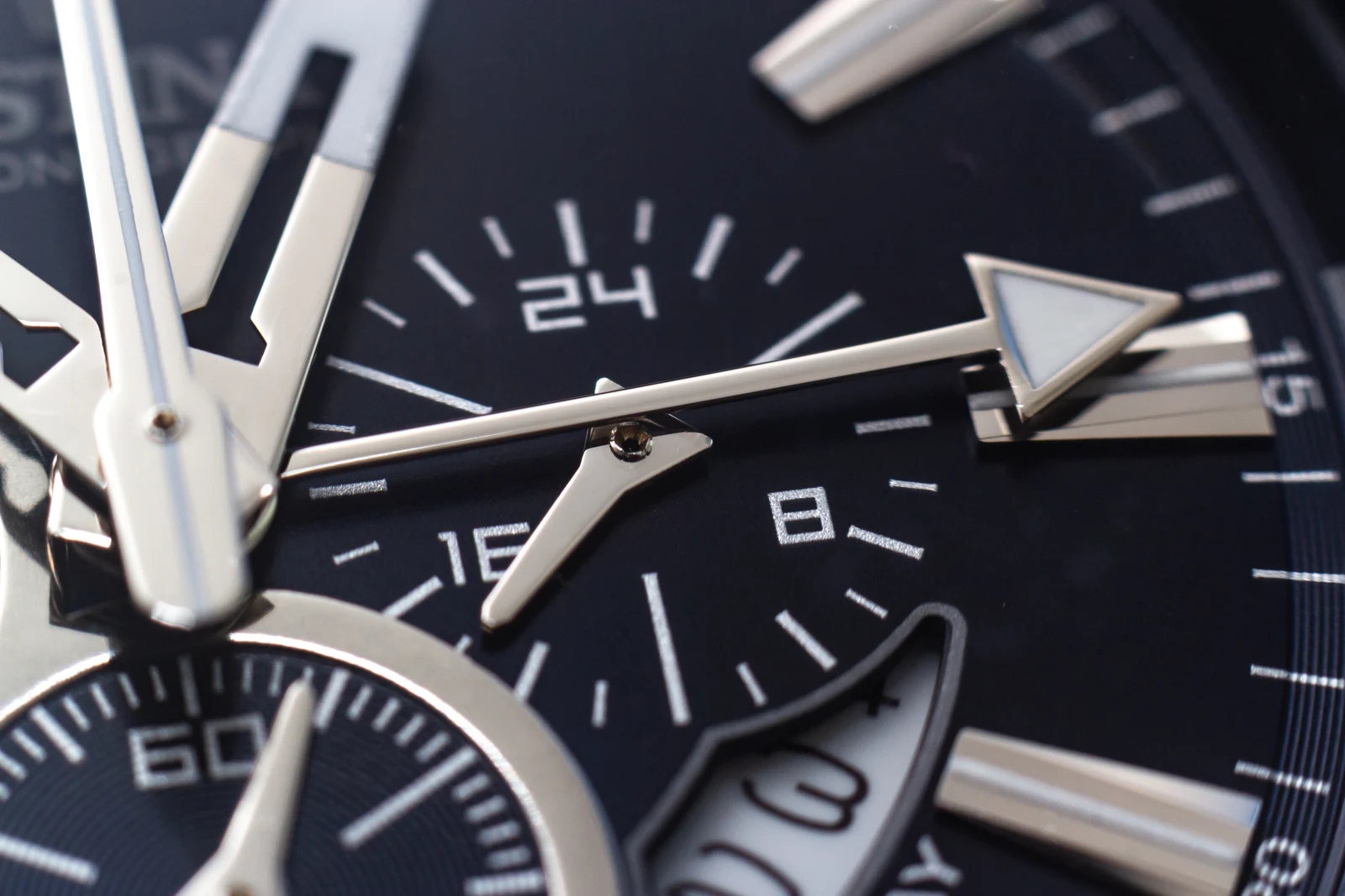 Close-up of watch hands and hour markers on a black dial