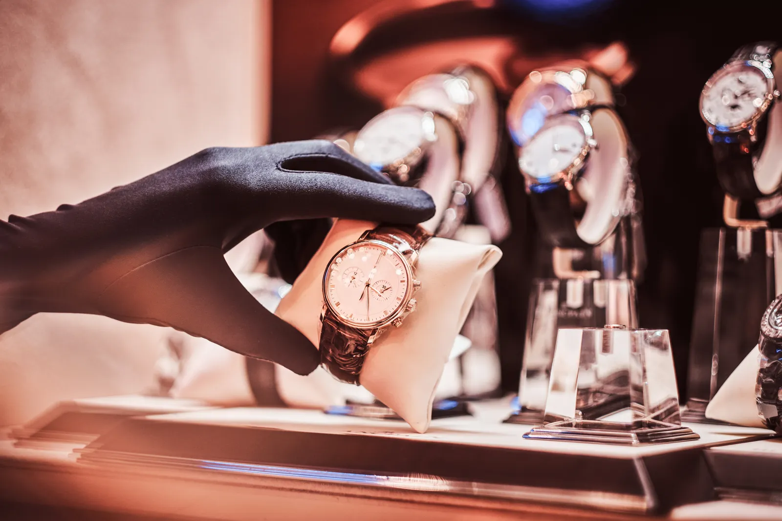 Gloved hand presenting a luxury gold watch in a boutique