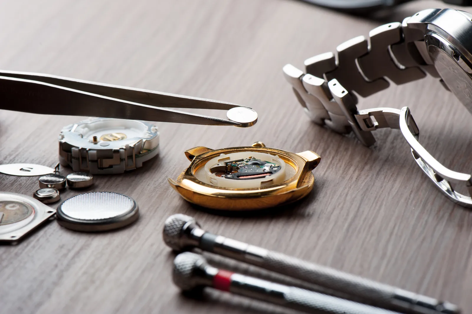 Tools to change a watch battery: tweezers, screwdrivers and an open case